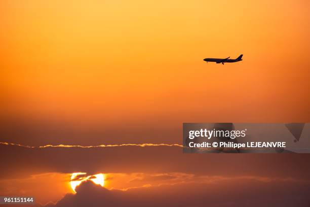 commercial plane flying against sunset - plane in sky stock-fotos und bilder