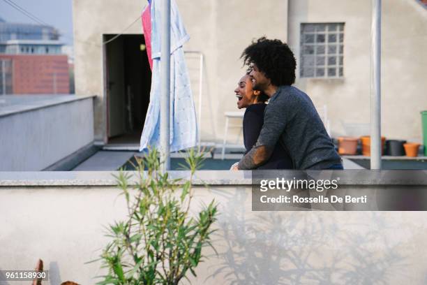 young beautiful couple hanging up laundry on rooftop terrace - afro man washing stock pictures, royalty-free photos & images