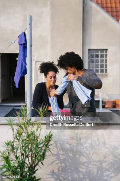 young beautiful couple hanging up laundry on rooftop terrace - afro man washing stock pictures, royalty-free photos & images