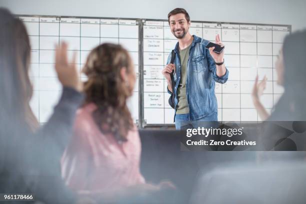 young man greeting colleagues in office - denim arrivals stock pictures, royalty-free photos & images