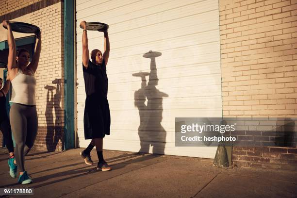 people with arms raised carrying weights equipment - heshphoto stockfoto's en -beelden