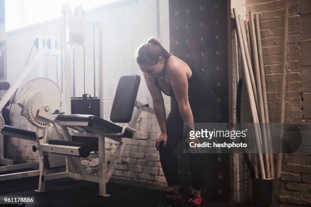 woman in gym, hands on knees exhausted - heshphoto stock-fotos und bilder
