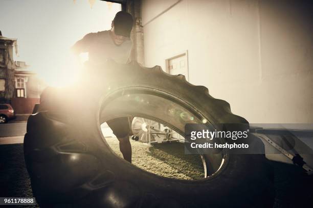 man lifting large tire - heshphoto stock-fotos und bilder