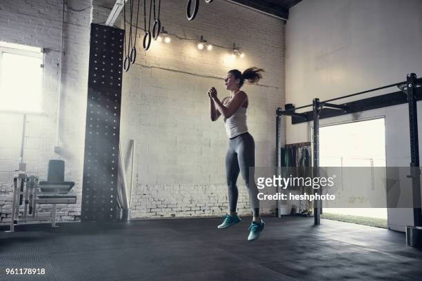 woman in gym jumping in mid air - heshphoto foto e immagini stock