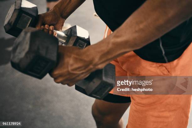 cropped view of man using dumbbells - heshphoto foto e immagini stock