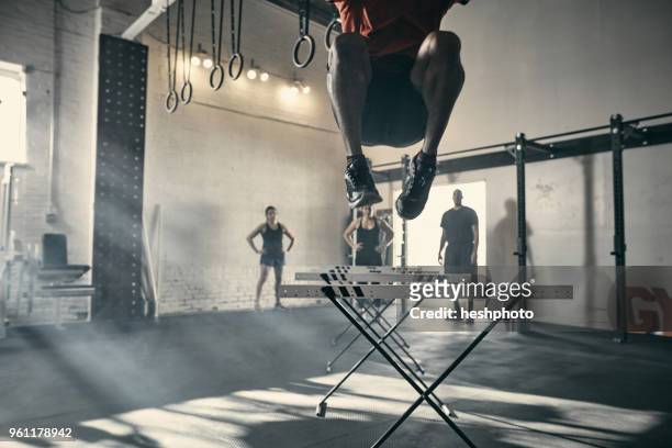 man in mid air jumping hurdles in gym - heshphoto stock-fotos und bilder