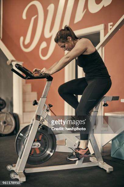 woman using exercise bike in gym - heshphoto fotografías e imágenes de stock