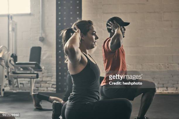 people exercising in gym, hands behind head lunging - heshphoto fotografías e imágenes de stock