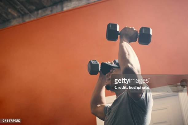man using dumbbells in gym - heshphoto foto e immagini stock