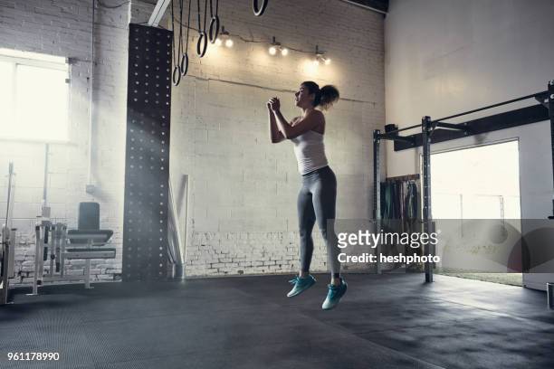 woman in gym jumping in mid air - heshphoto stock-fotos und bilder