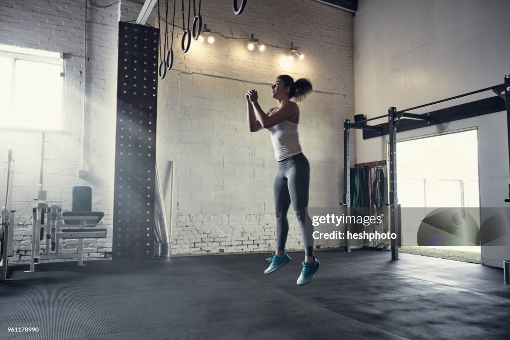 Woman in gym jumping in mid air