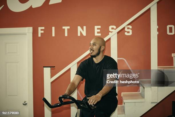 man in gym using exercise bike - heshphoto stock-fotos und bilder