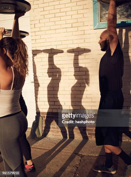 people with arms raised carrying weights equipment, side view - heshphoto stock-fotos und bilder