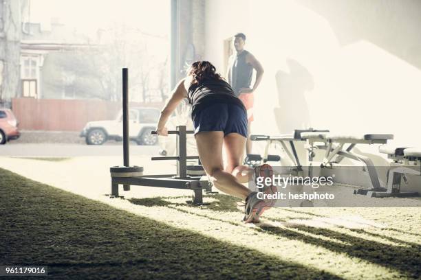 woman in gym using exercise equipment - heshphoto stockfoto's en -beelden