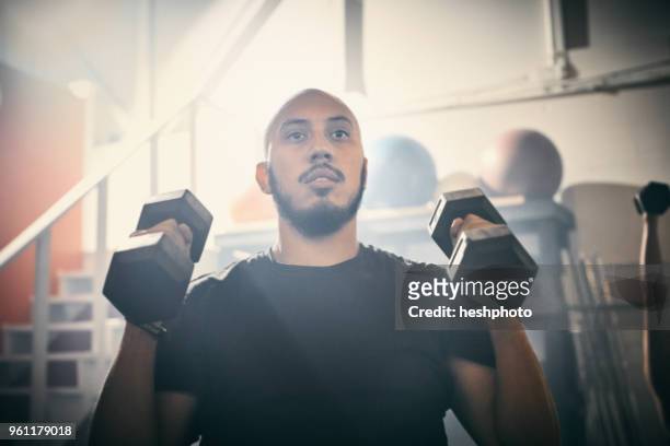 man using dumbbells in gym - heshphoto stock-fotos und bilder