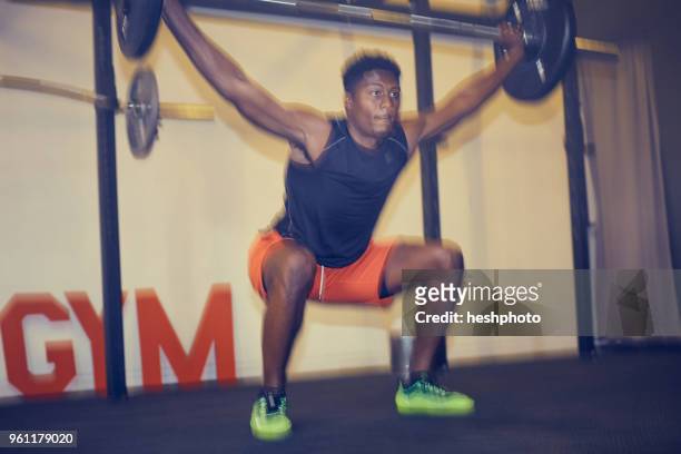 man in gym weightlifting using barbell, defocused - heshphoto stock-fotos und bilder