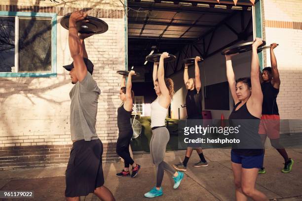 group of people with arms raised carrying weights equipment, side view - heshphoto stock-fotos und bilder