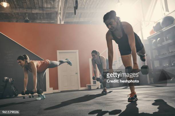 group of women in gym exercising using dumbbells - heshphoto stockfoto's en -beelden