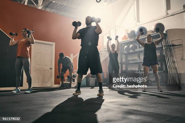 man using dumbbells in gym - heshphoto stockfoto's en -beelden