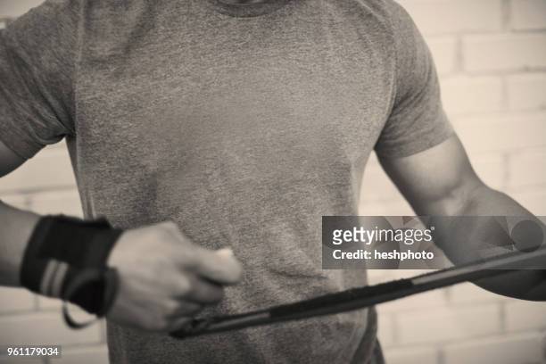 cropped view of man strapping hands with weightlifting straps - heshphoto stock-fotos und bilder