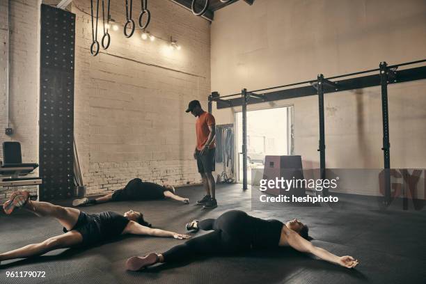 gym instructor supervising people doing floor exercises in gym - heshphoto stockfoto's en -beelden