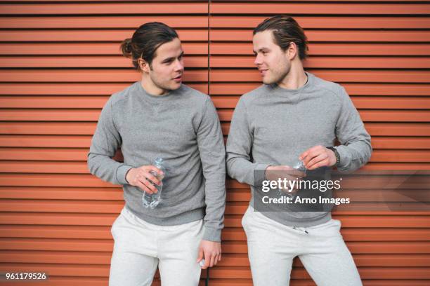 young adult male twins taking a training break, chatting - identical twins stockfoto's en -beelden