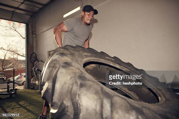 man lifting large tire - heshphoto stockfoto's en -beelden