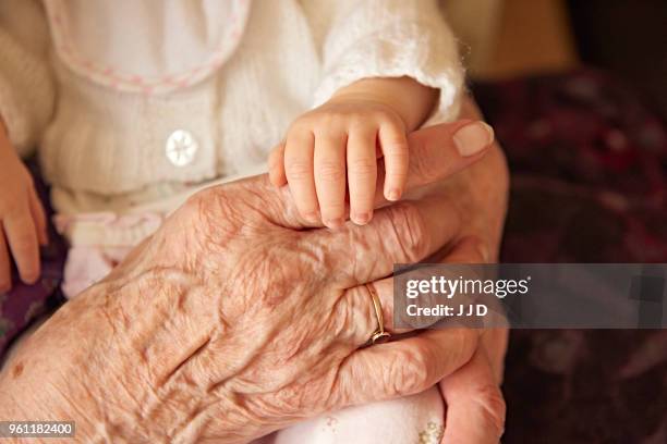 senior woman holding baby great granddaughter, close up of hands - holding newborn stock pictures, royalty-free photos & images