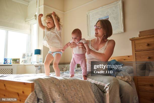 woman on bed playing with baby and toddler daughters - kids in undies stock pictures, royalty-free photos & images