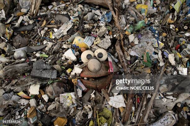 This photo taken on May 19, 2018 shows a stuffed toy of the Sesame Street character "Elmo" surrounded by plastic waste on a beach on the Freedom...