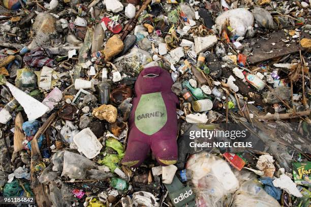 This photo taken on May 19, 2018 shows a stuffed toy of "Barney the Dinosaur" surrounded by plastic waste on a beach on the Freedom island critical...