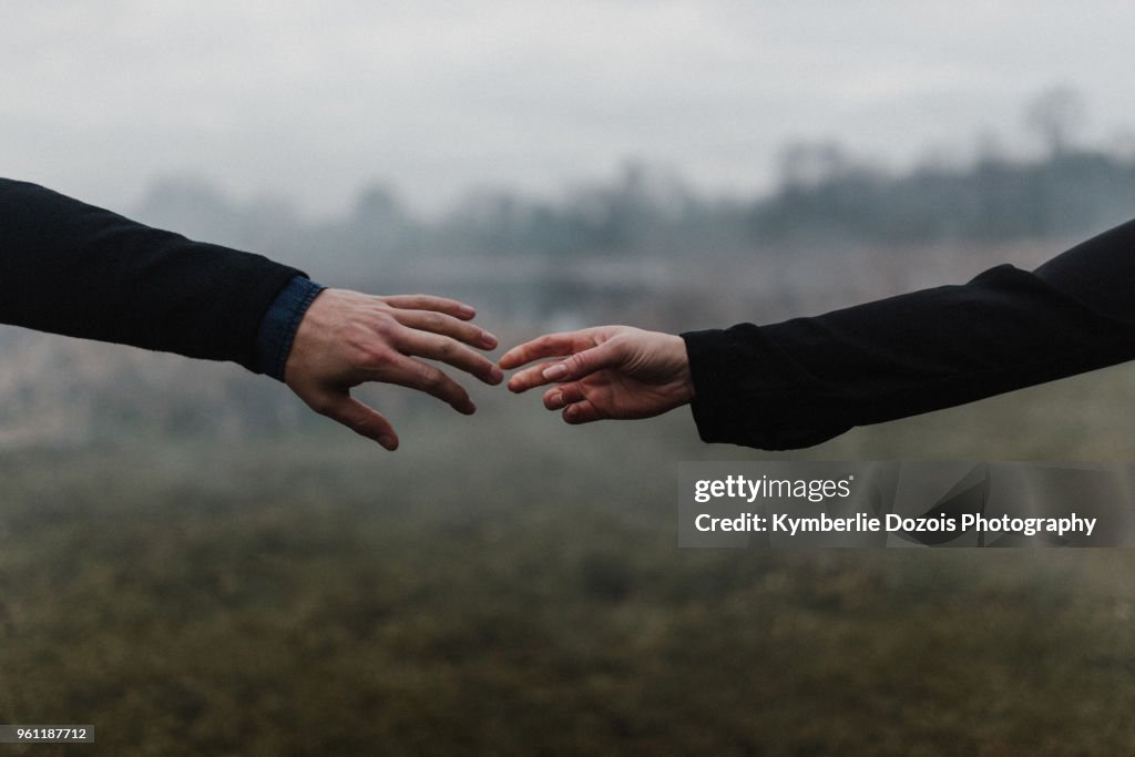 Cropped view of young couple holding hands, fingers touching