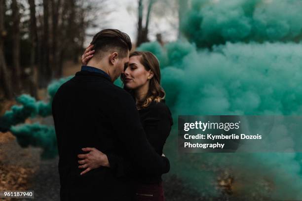 young couple kissing in forest by green smoke cloud - passion stock pictures, royalty-free photos & images