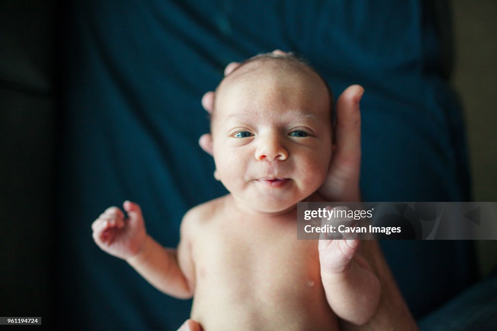 Overhead portrait of newborn baby boy held by father in hospital