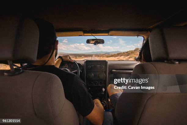 rear view of man and woman traveling in off-road vehicle on road - side by side atv stock pictures, royalty-free photos & images