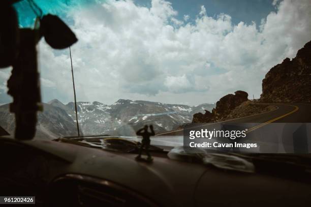 car moving on mountain road against cloudy sky at rocky mountain national park - rocky road stock pictures, royalty-free photos & images