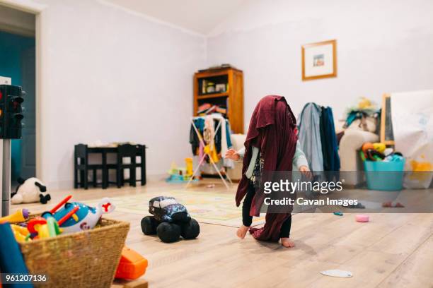 playful toddler running with towel on head at home - toddler mess stock-fotos und bilder