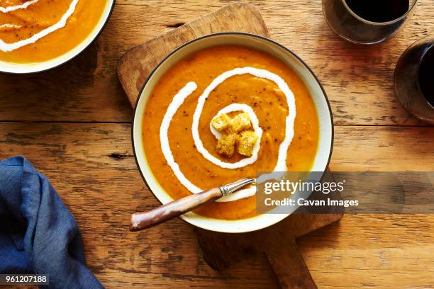 overhead view of butternut squash soup in bowl on cutting board at table - バターナットスクワッシュスープ ストックフォトと画像