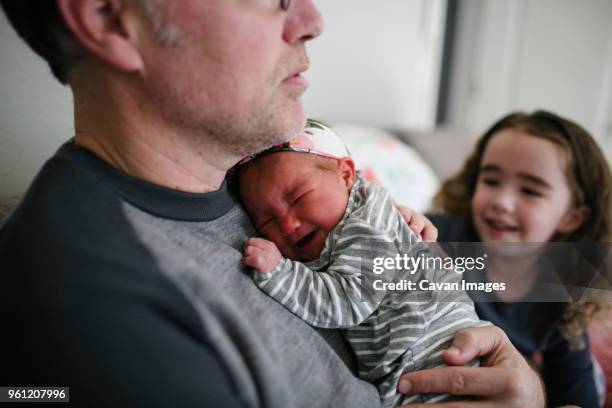 father comforting crying baby girl by daughter at home - crying sibling stock pictures, royalty-free photos & images