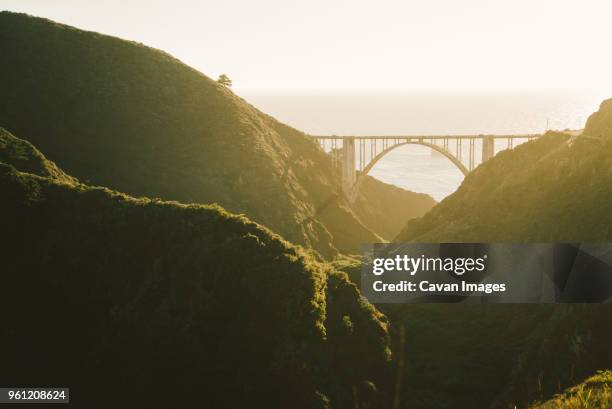 bixby creek bridge amidst mountains against clear sky - bixby bridge foto e immagini stock