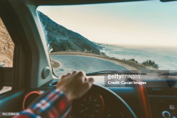 cropped image of man driving car on road by sea - car dashboard windscreen stock pictures, royalty-free photos & images