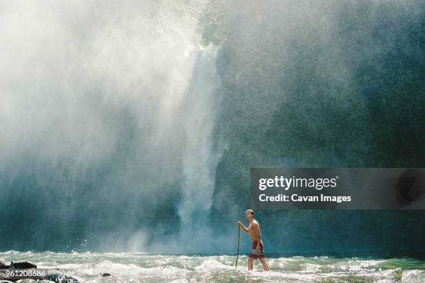 man walking in shallow water against waterfall - ifugao province stock pictures, royalty-free photos & images