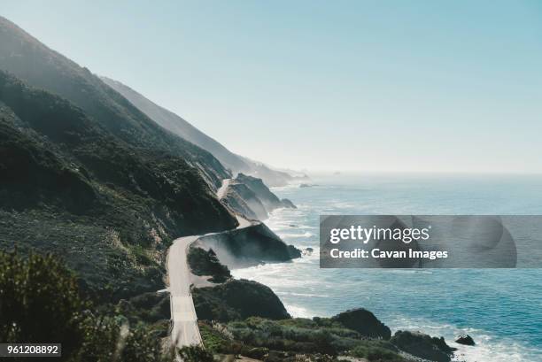 rocky mountain by sea against clear blue sky - big sur stock pictures, royalty-free photos & images