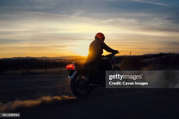 man riding motorcycle on field against sky during sunset - motorbike riding stock pictures, royalty-free photos & images