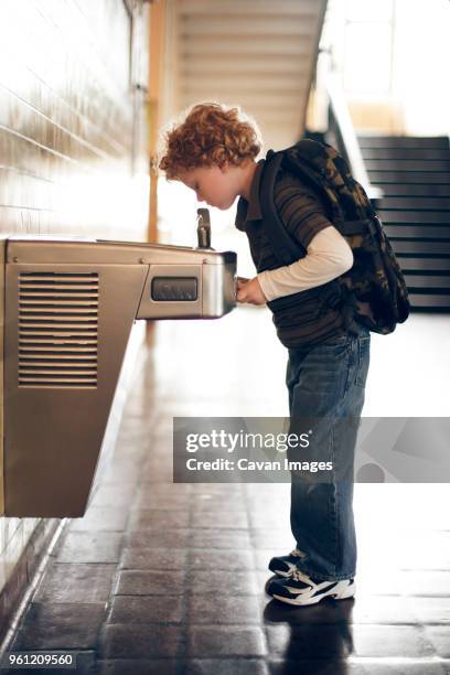 side view of boy drinking from water fountain at school - fuente estructura creada por el hombre fotografías e imágenes de stock