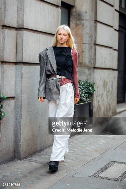 Model Hunter Schafer wears an asymmetrical outfit with a blazer only on one shoulder and loose white pants during London Fashion Week Spring/Summer...