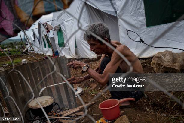 Displaced Marawi resident cook a meal in front of his shelter on the eve of Ramadan at the Sarimanok tent city on May 16, 2018 in Marawi,...