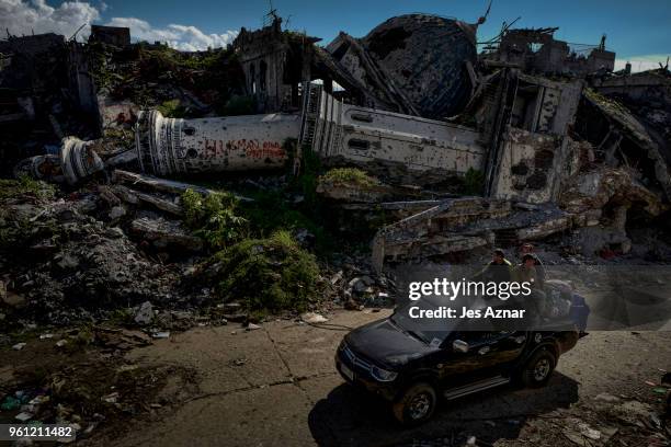 Displaced residents pass by a destroyed mosque on May 10, 2018 in Marawi, Philippines. With their homes destroyed and their properties looted or...