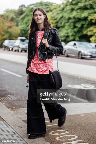 Model Irina Shnitman wears a cropped black leather jacket, red camo shirt, black purse, and black raver pants during London Fashion Week...