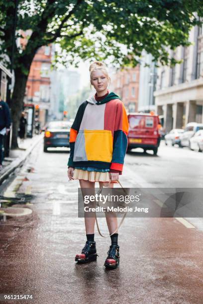 Model Jess PW wears a color-block hoodie, short skirt, tan J.W. Anderson bag, and black chunky Prada boots during London Fashion Week Spring/Summer...